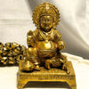 Gold-colored statue of a seated figure on a white background