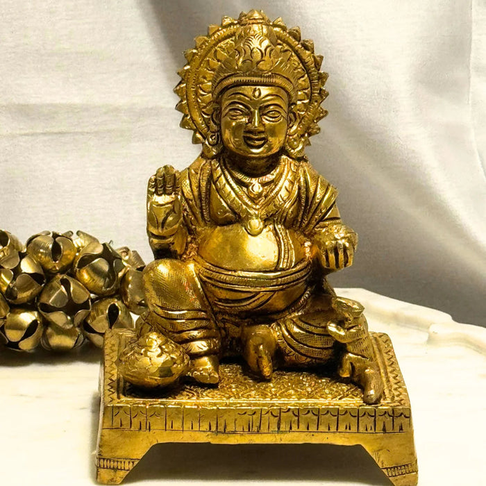Gold-colored statue of a seated figure on a white background