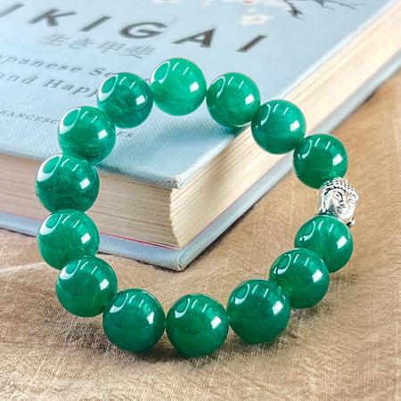 Green beaded bracelet with a silver Buddha charm on a book