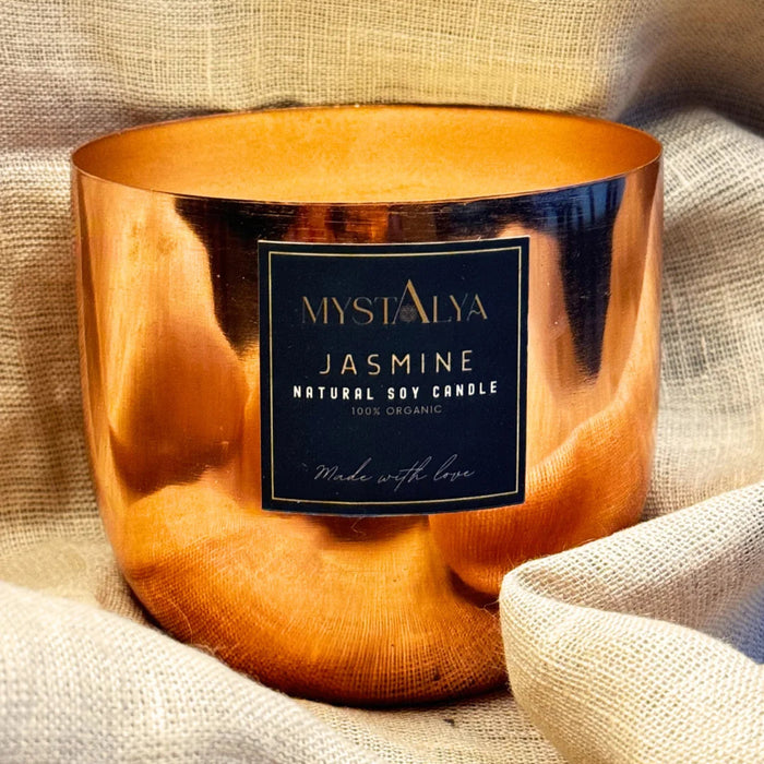 Copper candle holder with a label on a textured fabric background