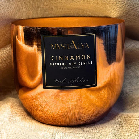 Copper-colored candle with a label on a textured fabric background