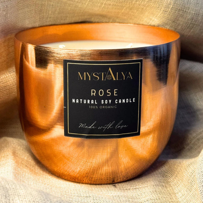 Mystalya Rose natural soy candle in a copper holder on a textured fabric background