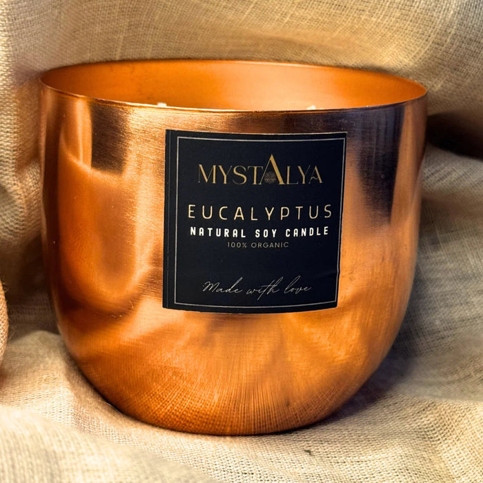 Copper candle holder with a label on a textured fabric background