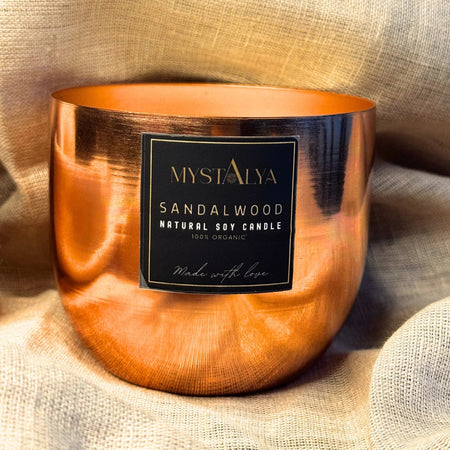 Mystalya sandalwood candle in a copper holder on a textured fabric background
