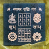 Decorative panel with symbols and text on a dark blue background, placed on a yellow fabric.