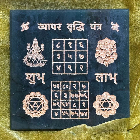 Decorative panel with symbols and text on a dark blue background, placed on a yellow fabric.