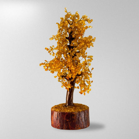 Decorative tree with yellow leaves on a wooden base against a gray background