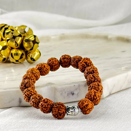 Brown beaded bracelet with a silver charm on a white surface