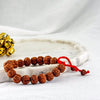 Bracelet with brown beads and red string on a white surface