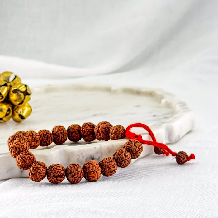 Bracelet with brown beads and red string on a white surface