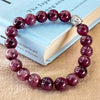 Red beaded bracelet with a silver Buddha charm on a book