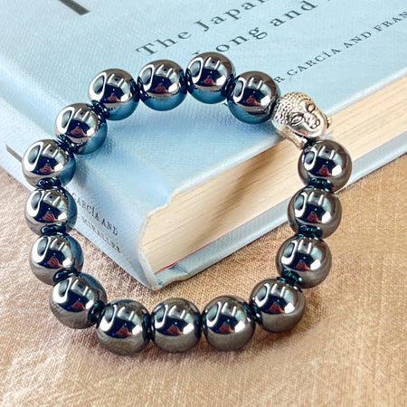 Silver beaded bracelet with Buddha charm on a book