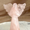 Pink angel sculpture on a marble surface with a wooden background
