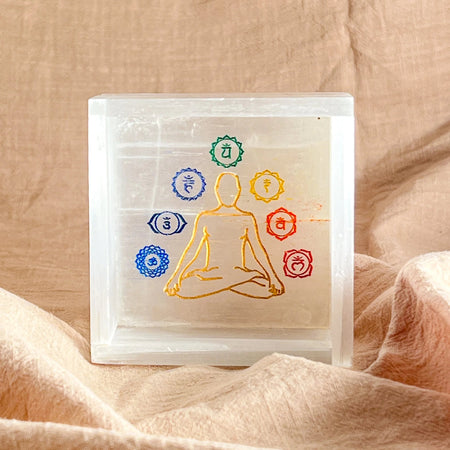 Transparent box with chakra symbols on a beige fabric background
