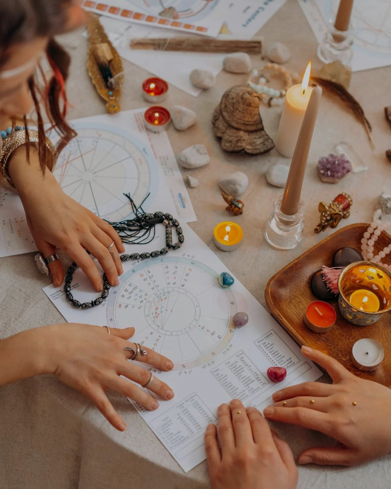 Two people sitting at a table with tarot cards, candles, and crystals in a mystical setting.