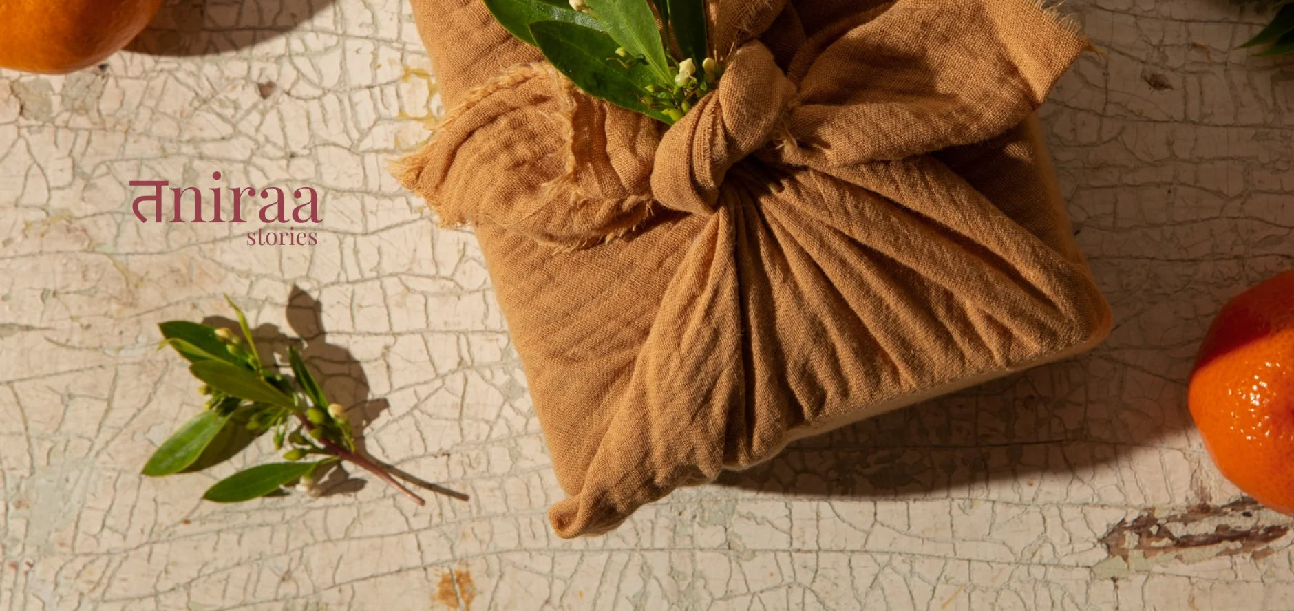 Brown fabric package with green leaves on a textured surface, featuring the brand 'Aniraa'.